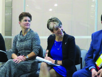 Three women and one man in business clothing reacting to something someone has said