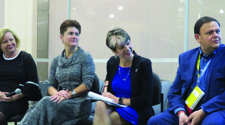 Three women and one man in business clothing reacting to something someone has said