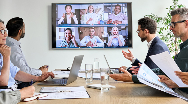 Employees on online conference video call on tv screen in meeting room.