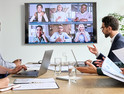 Employees on online conference video call on tv screen in meeting room.