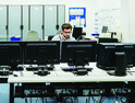 Man sitting behind an array of computer screens