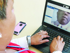 Woman on laptop looking at a man's closeup image